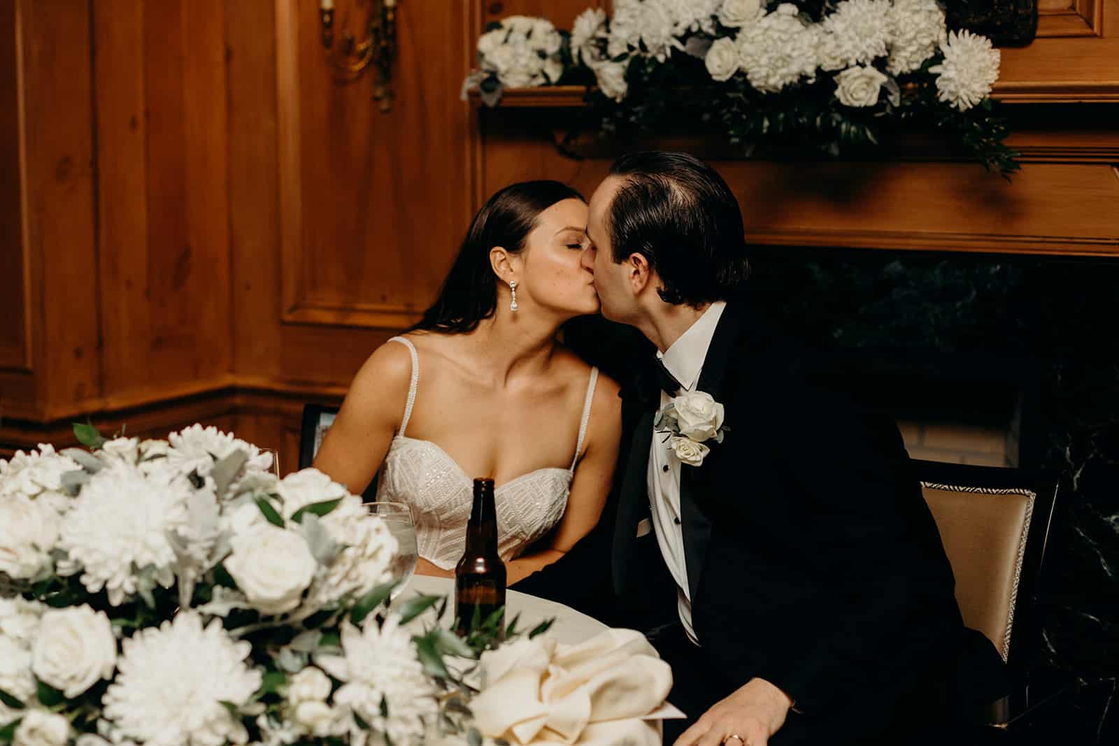 Bride and groom kissing at a table, Summer and Nicholas